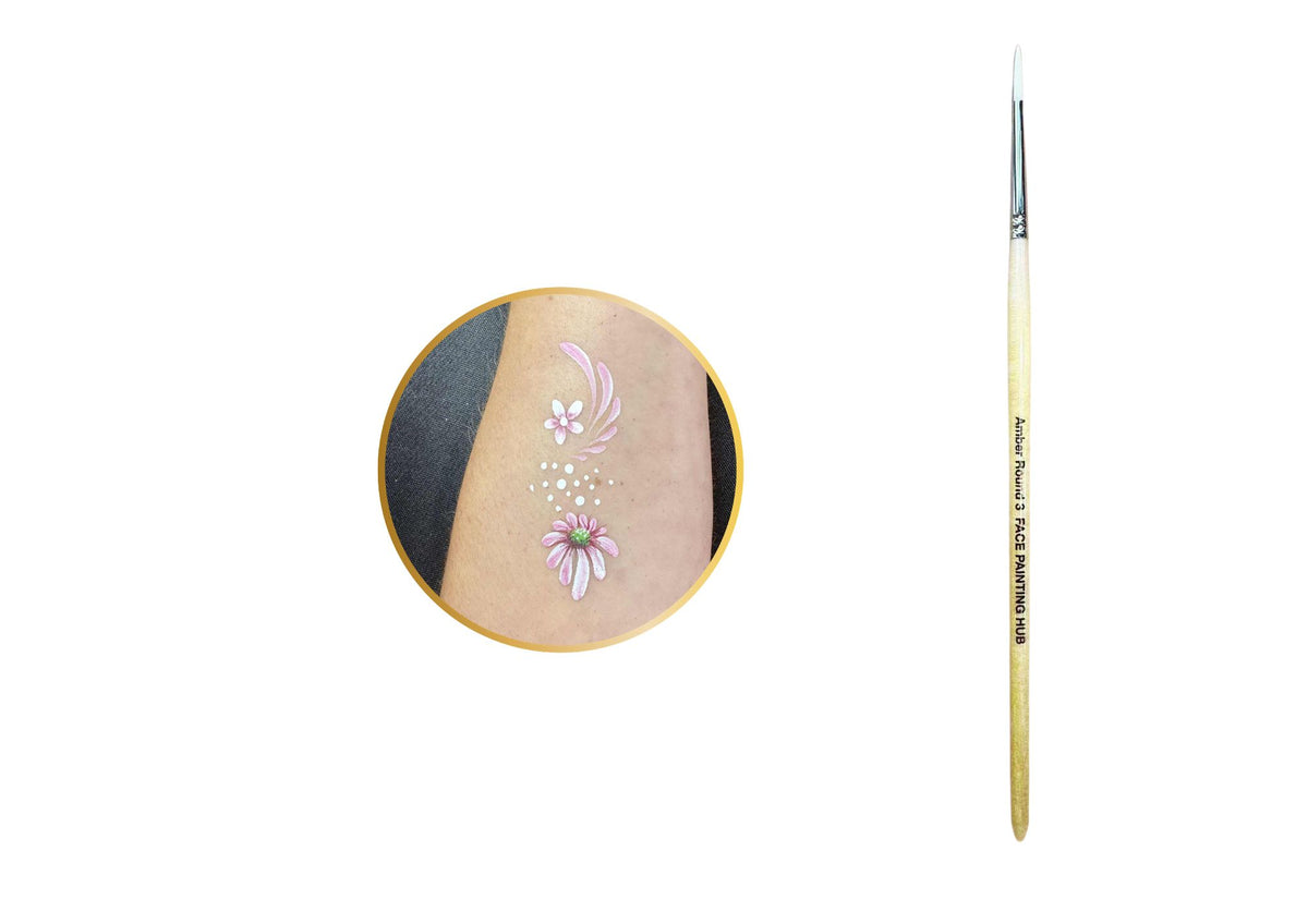 A fine-detail makeup brush shown vertically next to a circular inset demonstrating a floral body paint design applied to skin.